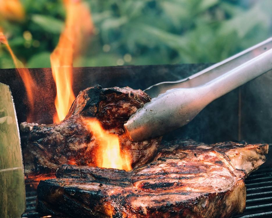 Ein Steak auf dem Grill mit hochlodernden Flammen