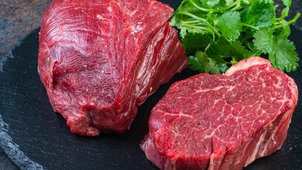 Zwei rohe, geschnittene Hüftsteaks angerichtet neben frischem Koriander.