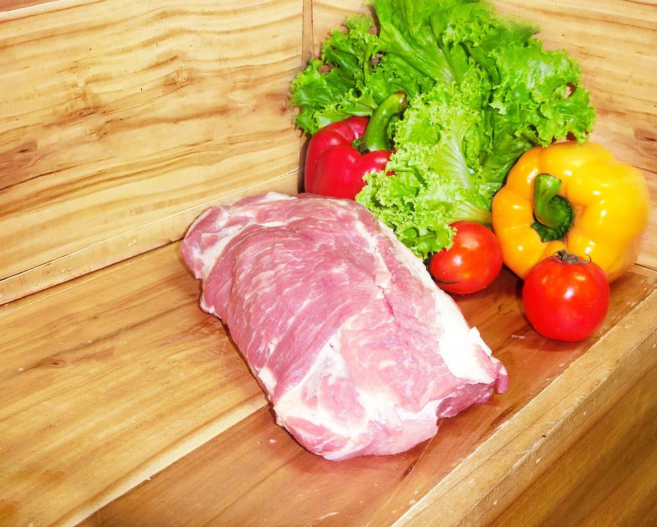 Schweinenacken vor einem hölzernen Hintergrund mit Gemüsedekoration